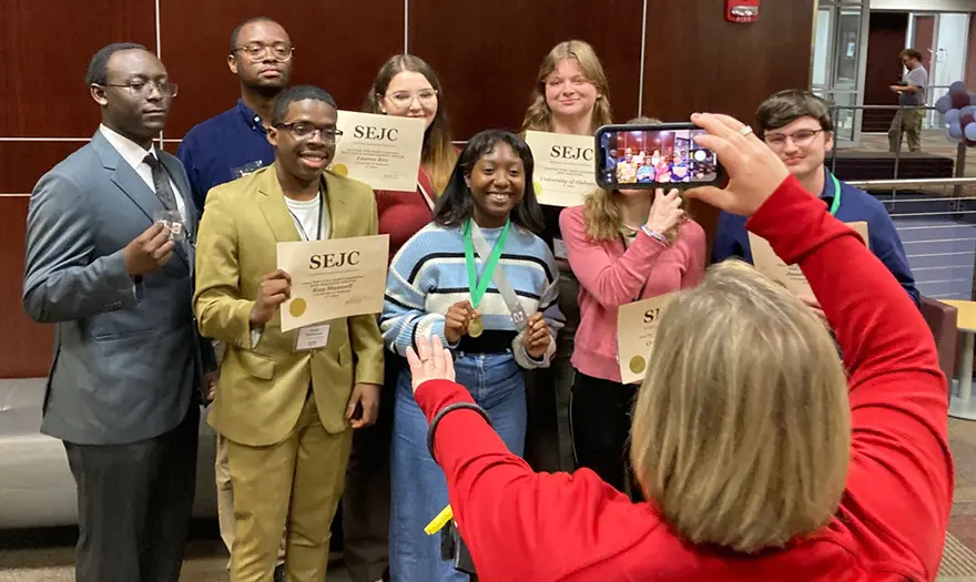 Students posing for photo holding medals and SEJC awards
